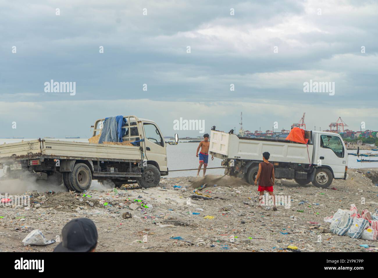 Quezon City, Quezon, Philippinen. November 2024. Ein LKW versucht, einen anderen LKW zu ziehen, der im Müllhaufen stecken geblieben ist. (Kreditbild: © Kenosis Yap/ZUMA Press Wire) NUR REDAKTIONELLE VERWENDUNG! Nicht für kommerzielle ZWECKE! Stockfoto