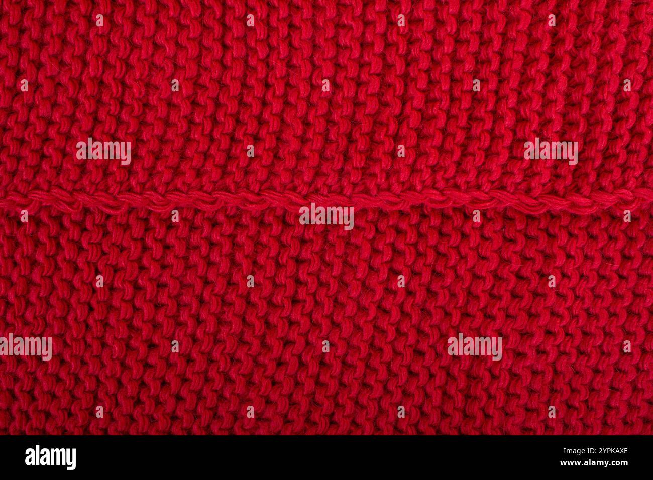 Wollgestrickter Hintergrund. Roter, strukturierter Pullover mit weihnachtlichem Stoff Stockfoto