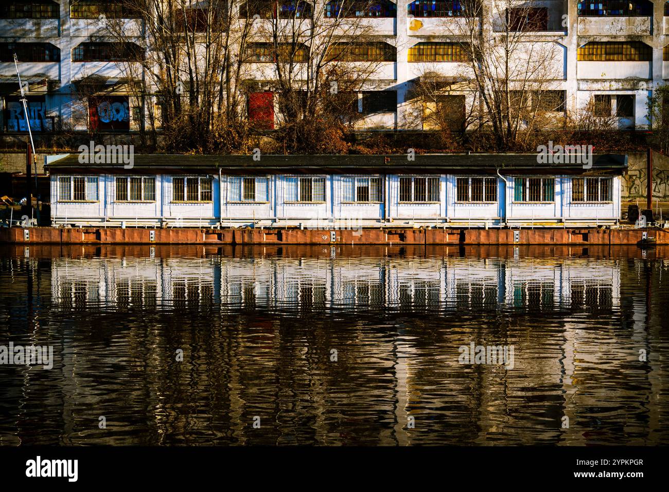 Riverside Structure mit Reflektionen, industriellem Hintergrund und herbstlichen Bäumen in urbaner Umgebung Stockfoto