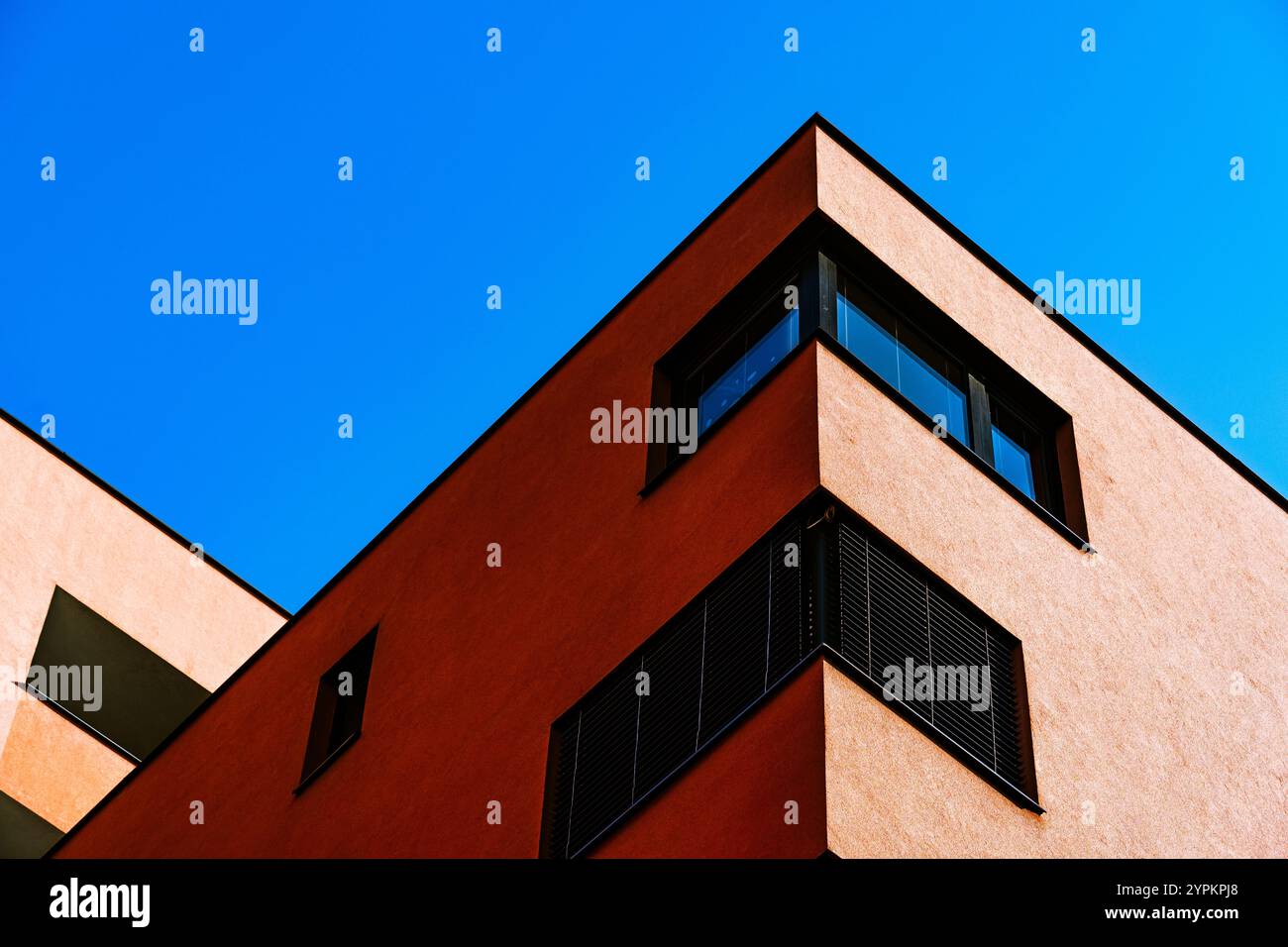 Lebendige Gebäudeecke mit kontrastierender rot-gelber Fassade und reflektierenden Fenstern Stockfoto