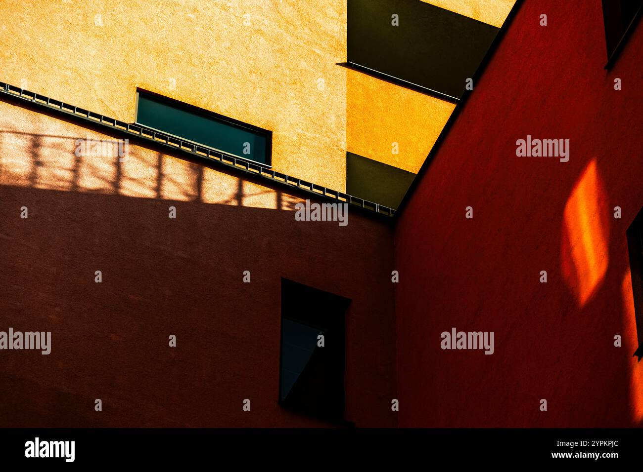 Lebendige Gebäudeecke mit kontrastierender rot-gelber Fassade und reflektierenden Fenstern Stockfoto