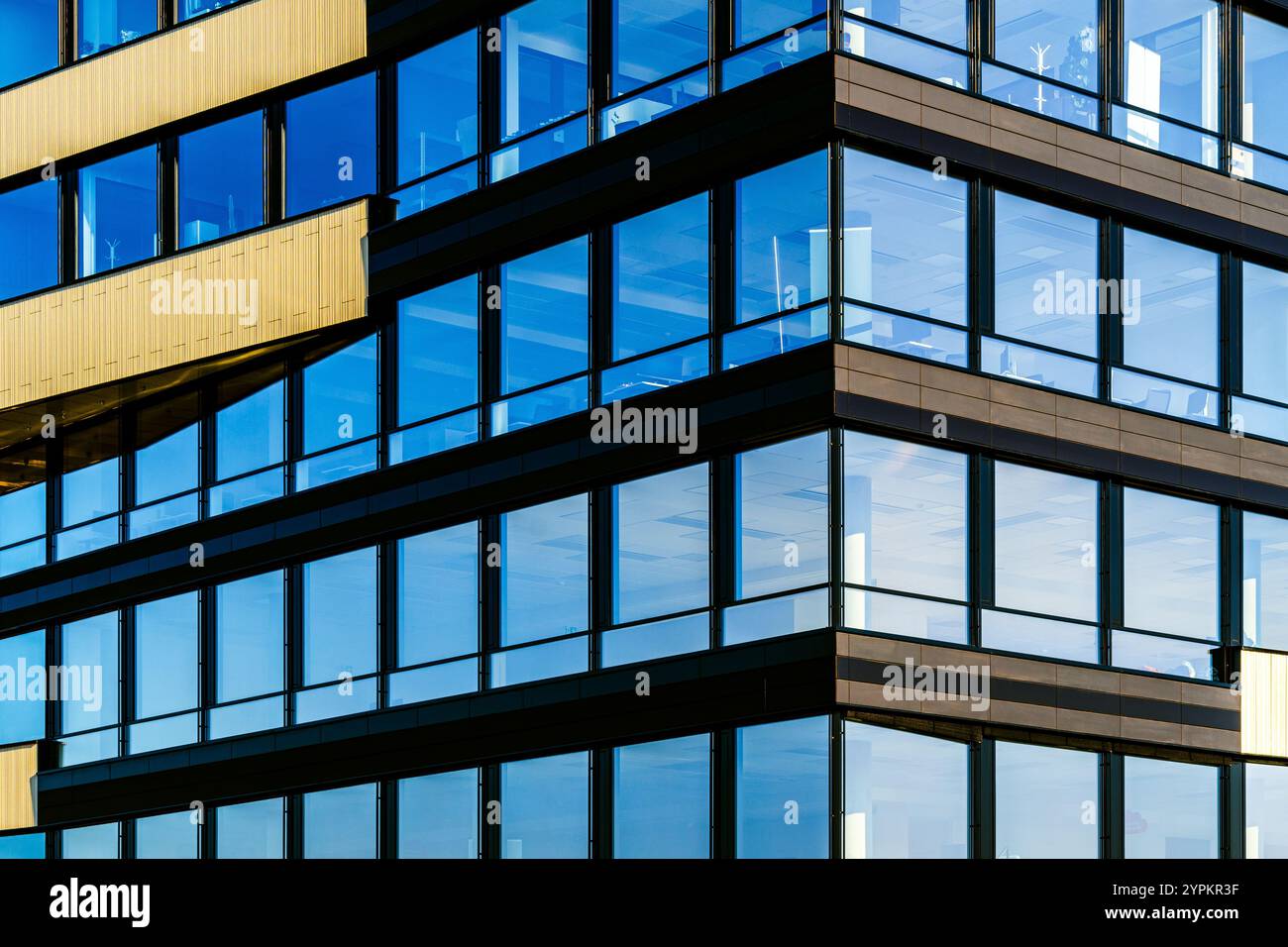 Modernes Glasgebäude mit reflektierenden Fenstern und goldenen Akzenten in urbaner Umgebung Stockfoto