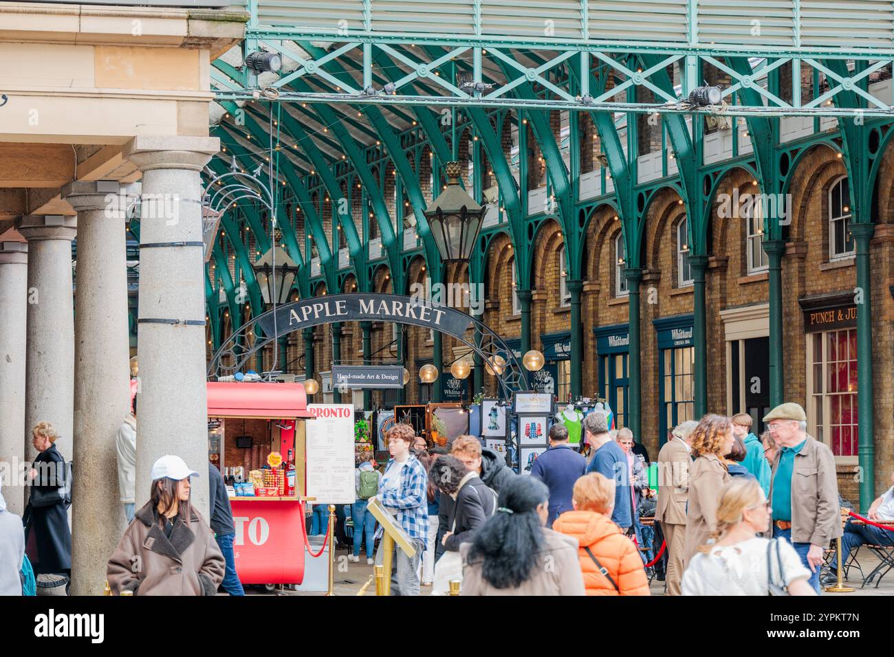 Apple Market at Covent Garden mit kunstvoll verzierten grünen Eisenwerken, klassischen Säulen und einer lebhaften Menschenmenge unter viktorianischer Architektur Stockfoto