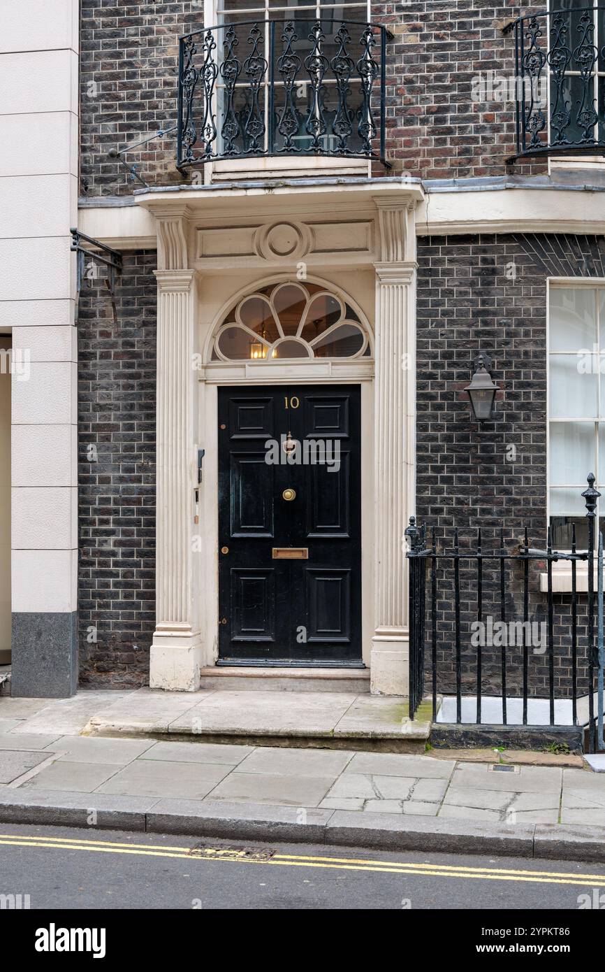 Historisches Londoner Stadthaus mit eleganter schwarzer Tür Nummer 10, georgianischer Architektur mit Fächerlicht und kunstvoller Steintür Stockfoto