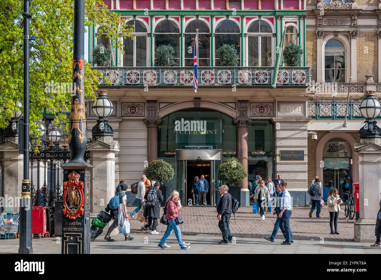 Der prunkvolle Eingang des Clermont Hotel London verfügt über einen viktorianischen Balkon mit Eisenwerk, dekorative Lampenpfosten und eine geschäftige Fußgängerzone Stockfoto