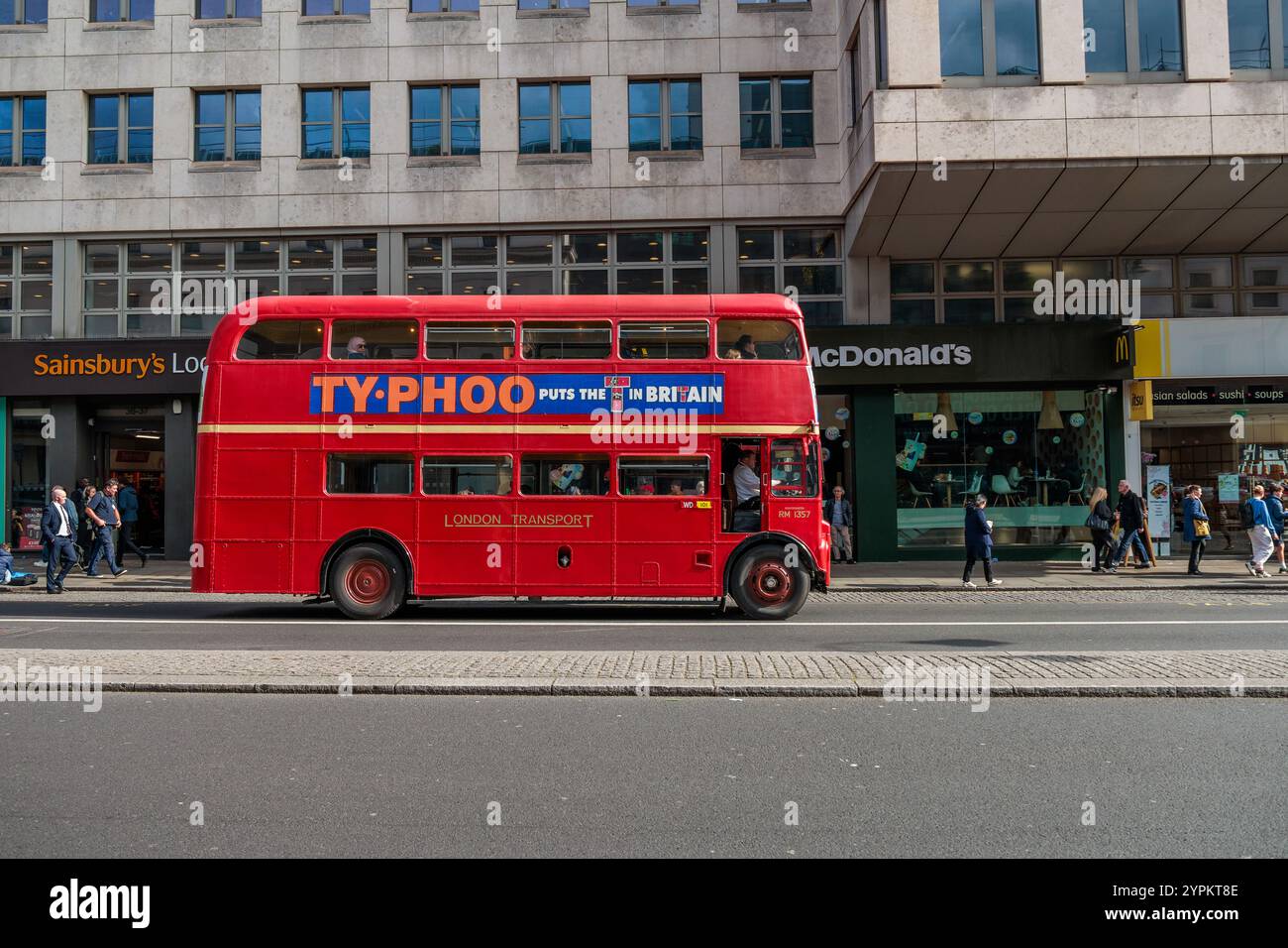 Der rote Routemaster-Touristenbus fährt am McDonalds Restaurant vorbei und wartet vor der belebten Londoner Straße mit Gästen auf Stockfoto