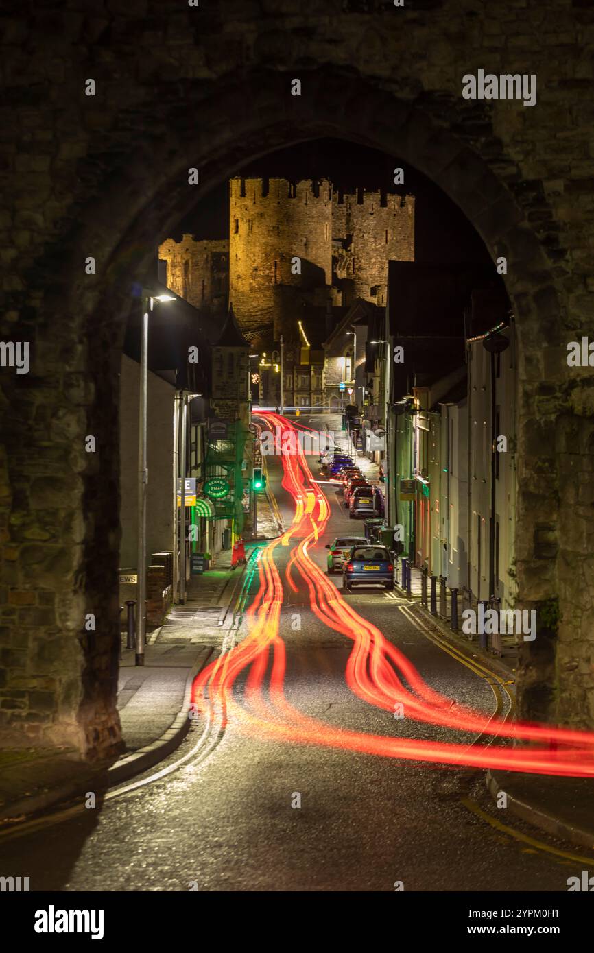 Das Auto leuchtet durch einen Bogengang in den Stadtmauern, der Conwy Castle, Wales, zeigt Stockfoto