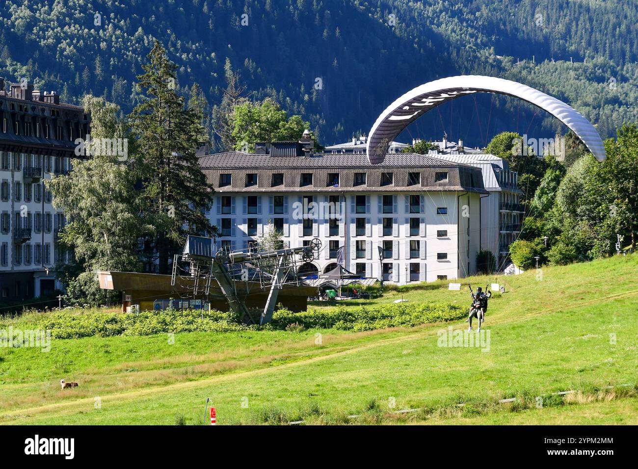 Tandem-Gleitschirmfliegen auf einer Wiese in der Nähe des Zentrums der Alpenstadt im Sommer, Chamonix, Haute Savoy, Auvergne Rhone Alpes, Frankreich Stockfoto