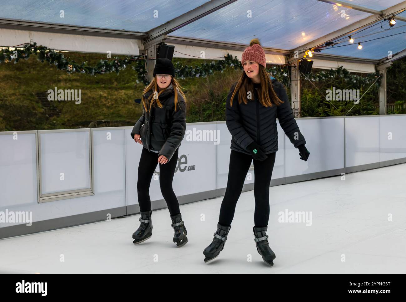 Zwei Mädchen genießen Spaß auf einer nachhaltigen, umweltfreundlichen Eislaufbahn, Dalkeith Country Park, Midlothian, Schottland, Großbritannien Stockfoto