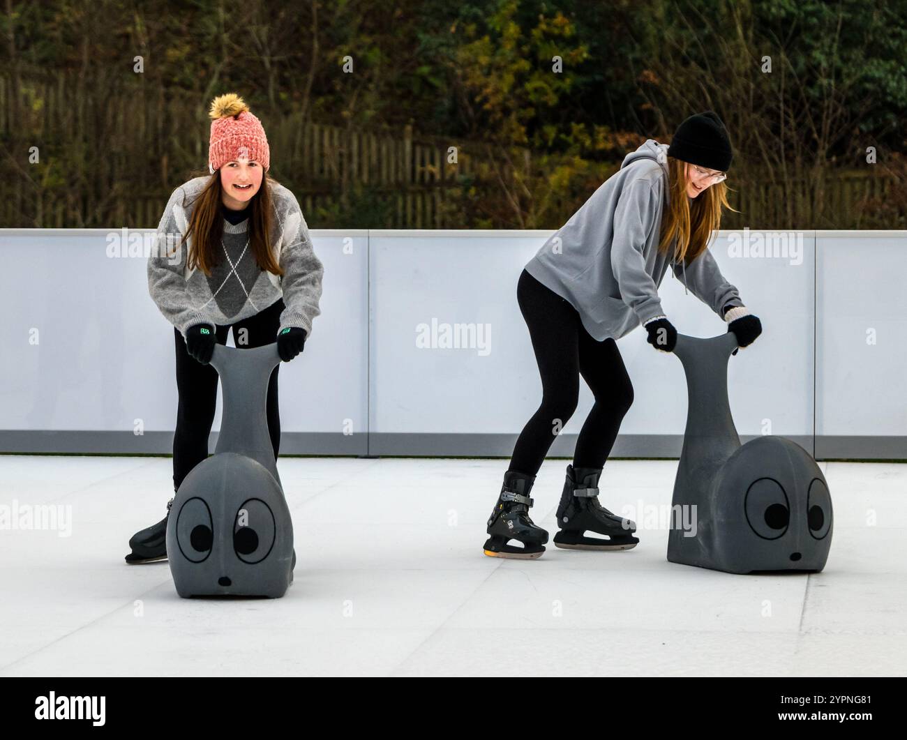 Zwei Mädchen genießen Spaß auf einer nachhaltigen, umweltfreundlichen Eislaufbahn, Dalkeith Country Park, Midlothian, Schottland, Großbritannien Stockfoto