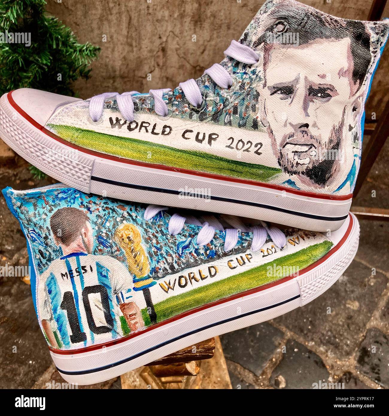Ein Paar Chuck Taylor All-Stars Sneakers mit dem Gesicht und dem Körper von Messi und den Worten „World Cup 2022“ - Smartphone-aufgenommenes Stockfoto