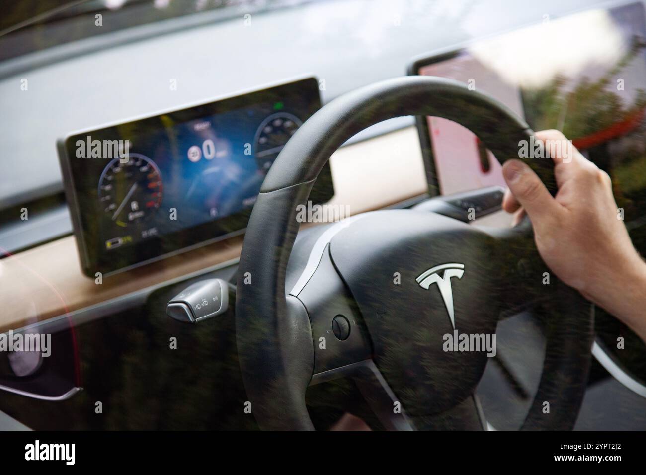 Vilnius, Litauen - 16-08-2024 - Innenraum des Tesla Model 3, Mannhand am Lenkrad und Armaturenbrett Stockfoto