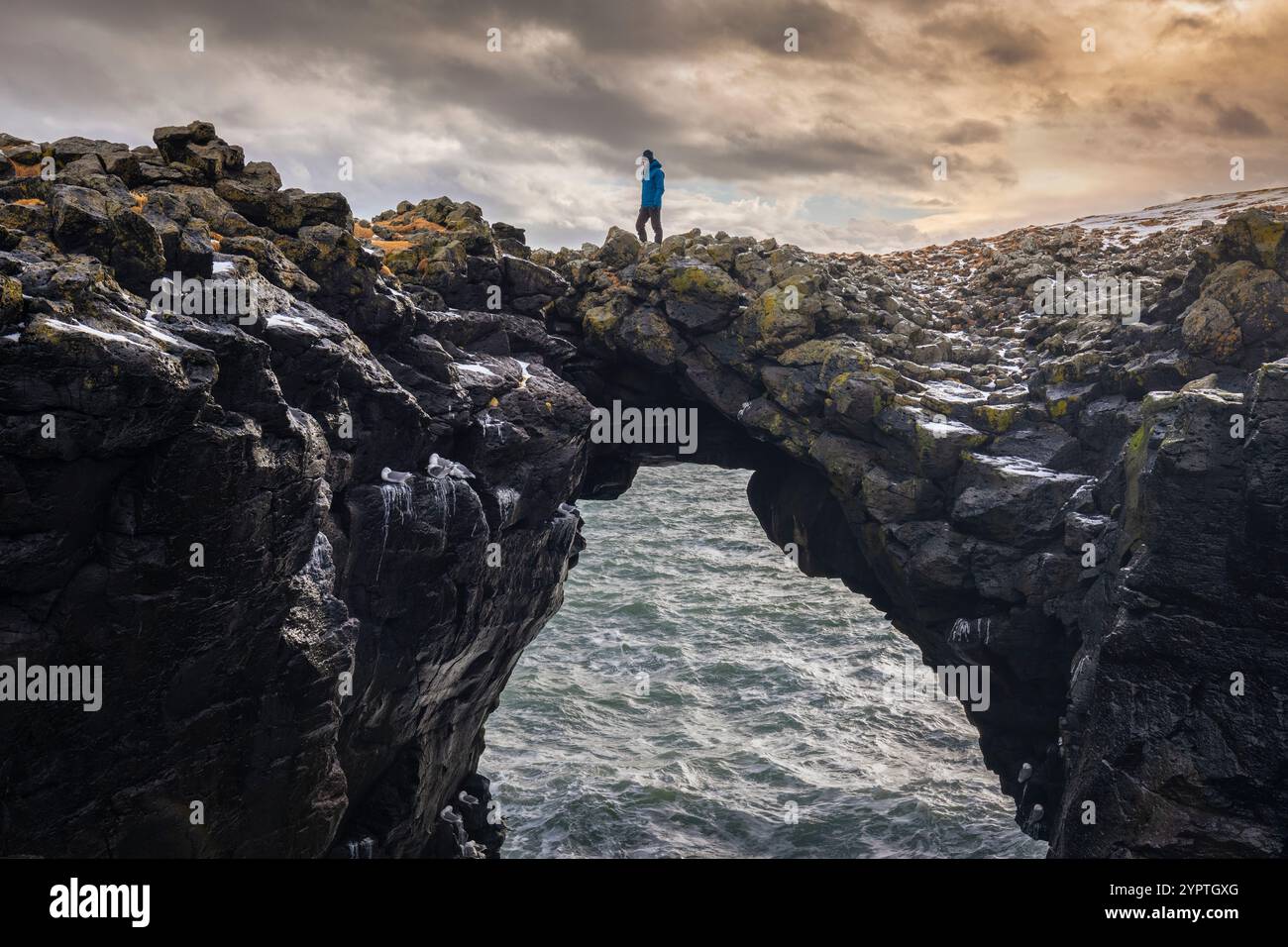 Blick auf einen Mann, der auf der Steinbrücke steht. Arnarstapi, Halbinsel Snæfellsnes, Island, Nordeuropa. Stockfoto