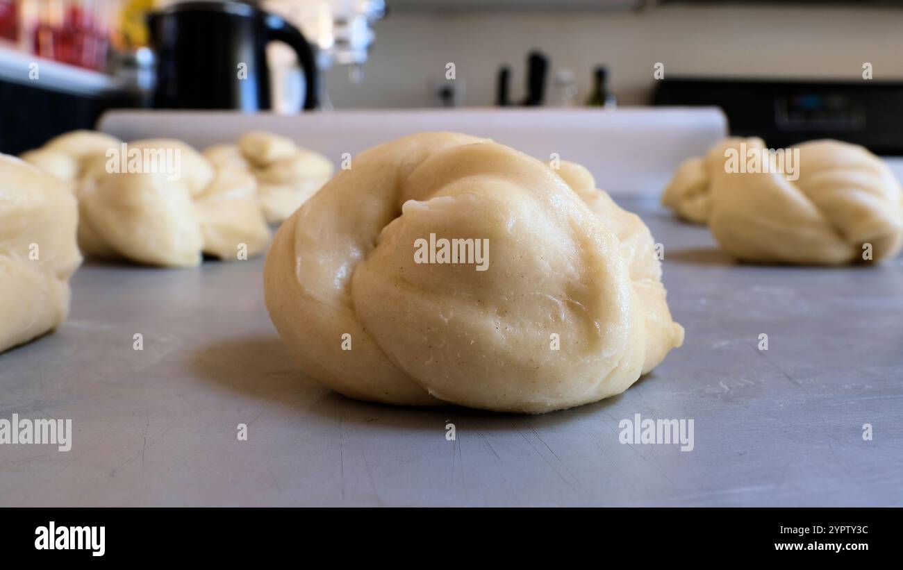 Zum Abendessen gebundene Hefe-Brötchen, die in Knoten auf einer Metallplatte liegen und beweisen, während der Teig vor dem Backen im Ofen aufgeht. Stockfoto
