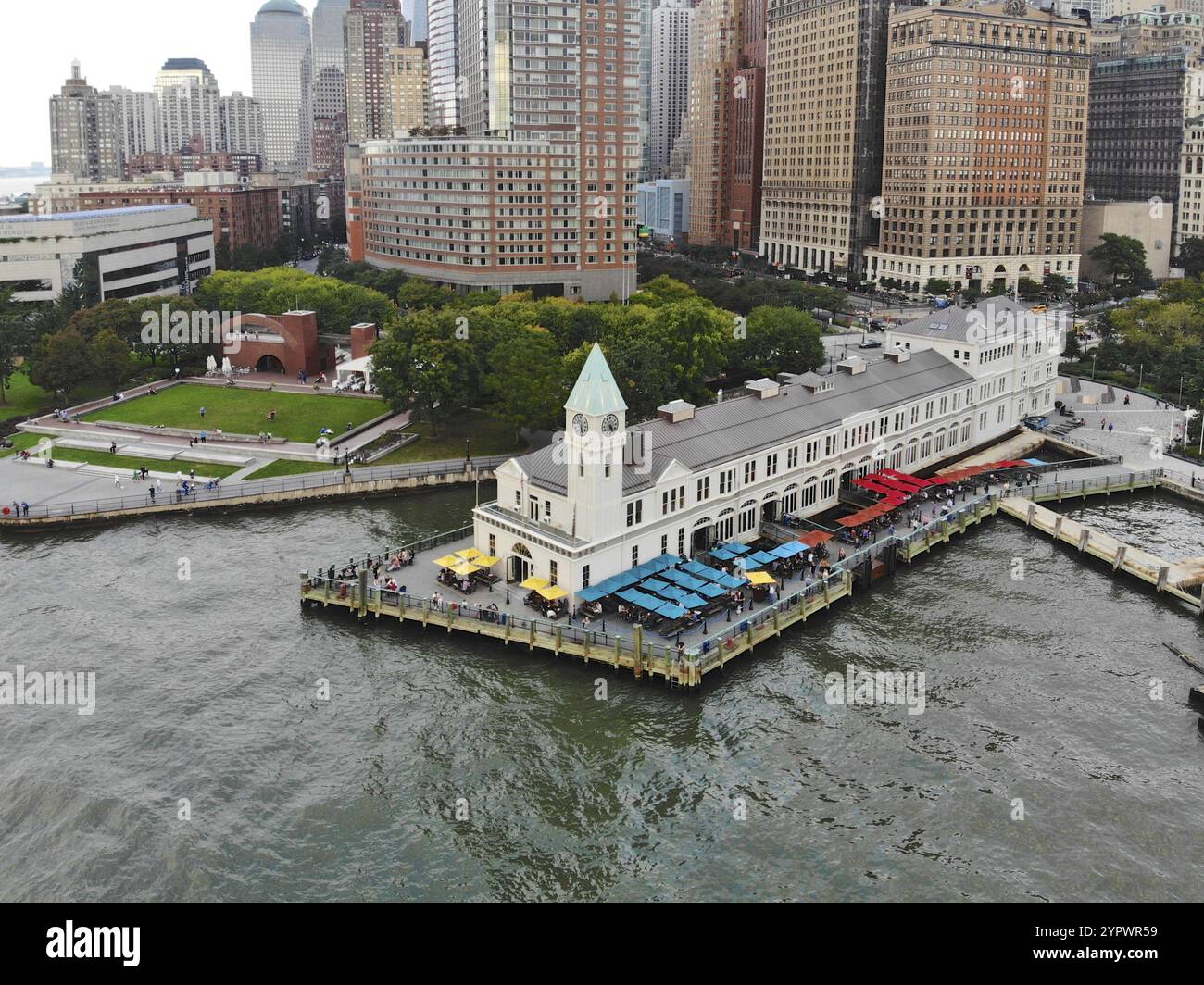 Aus der Vogelperspektive des Battery Park Pier A, der nach Liberty Island führt, kann man Menschen sehen, die in der Schlange stehen, um an Bord zu gehen, und auf Liberty Island loc blicken Stockfoto