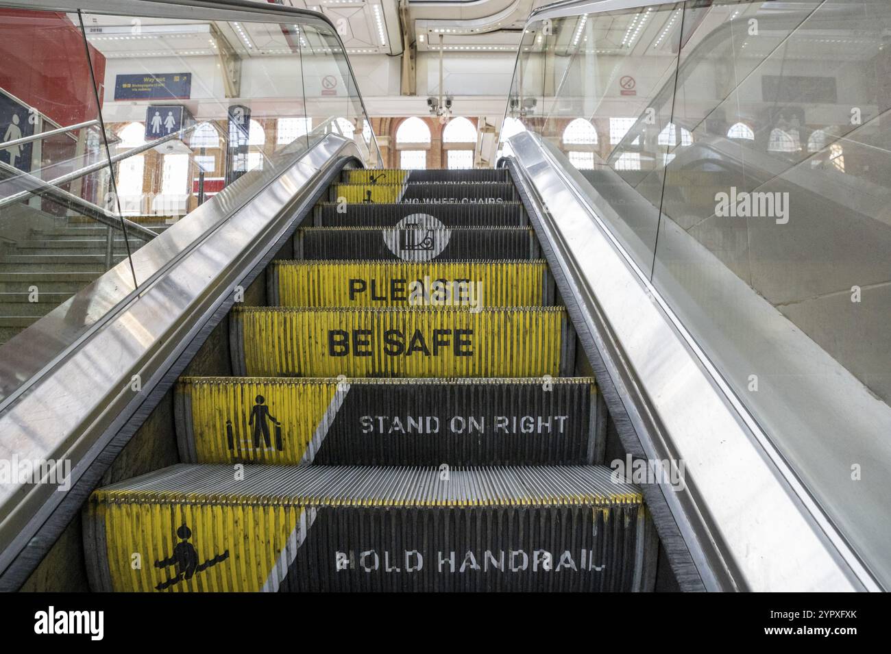 Rolltreppe am Bahnhof mit Meldung zur Trittstufe. Bitte seien Sie sicher, stehen Sie rechts und halten Sie den Handlauf. Warnschild und Warnung Stockfoto