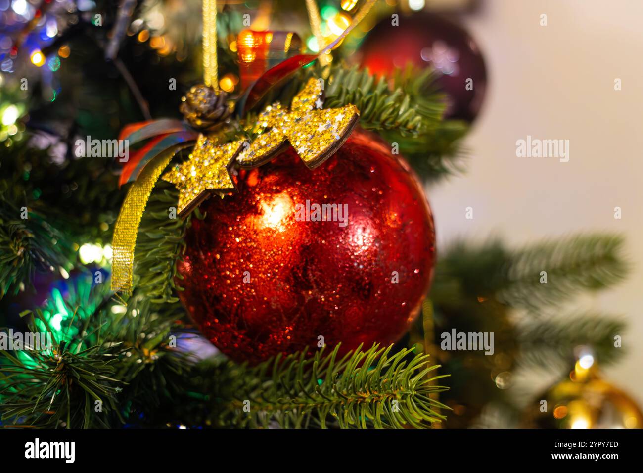 Nahaufnahme einer roten Kugel, die an einem Weihnachtsbaum hängt Stockfoto