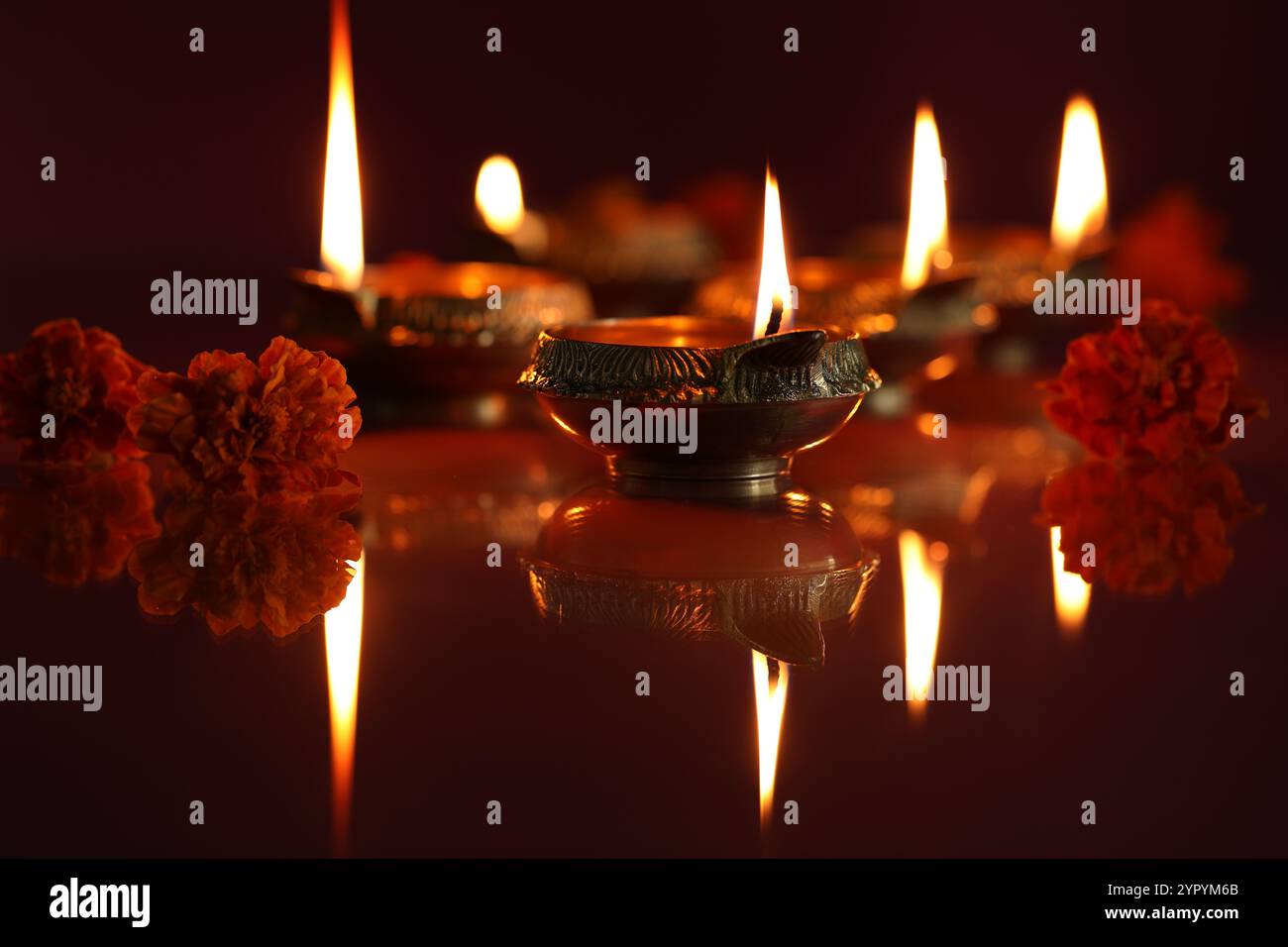 Diwali-Feier. Diya Lampen und schöne Blumen auf dunklem Hintergrund, Nahaufnahme Stockfoto