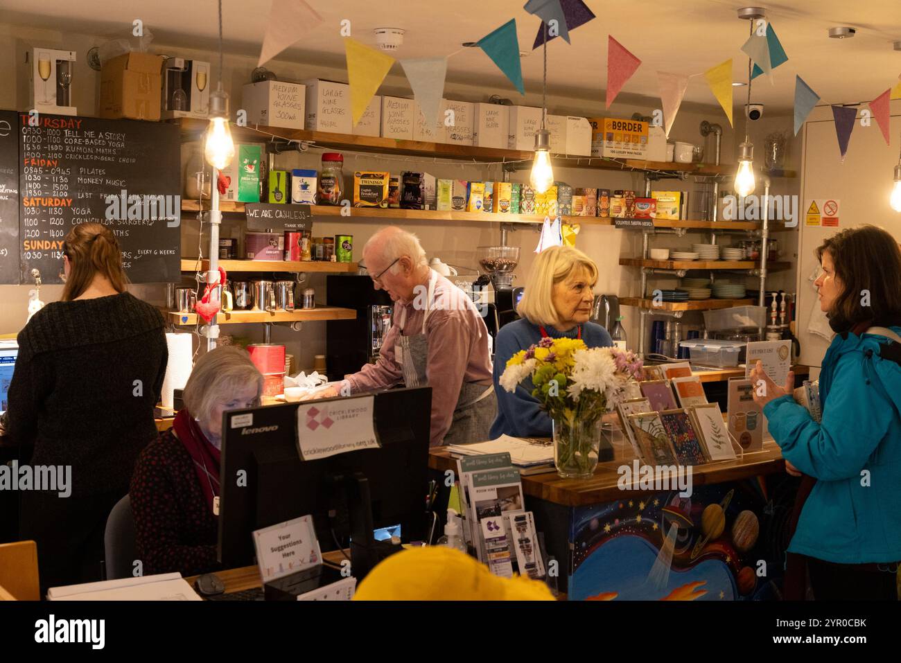 Ein Freiwilliger und ein Darlehensnehmer in der Cricklewood Library im Nordwesten Londons, die von der Gemeinde geleitet wird, nachdem der Brent council die Finanzierung eingestellt hat. Der Freiwillige li Stockfoto