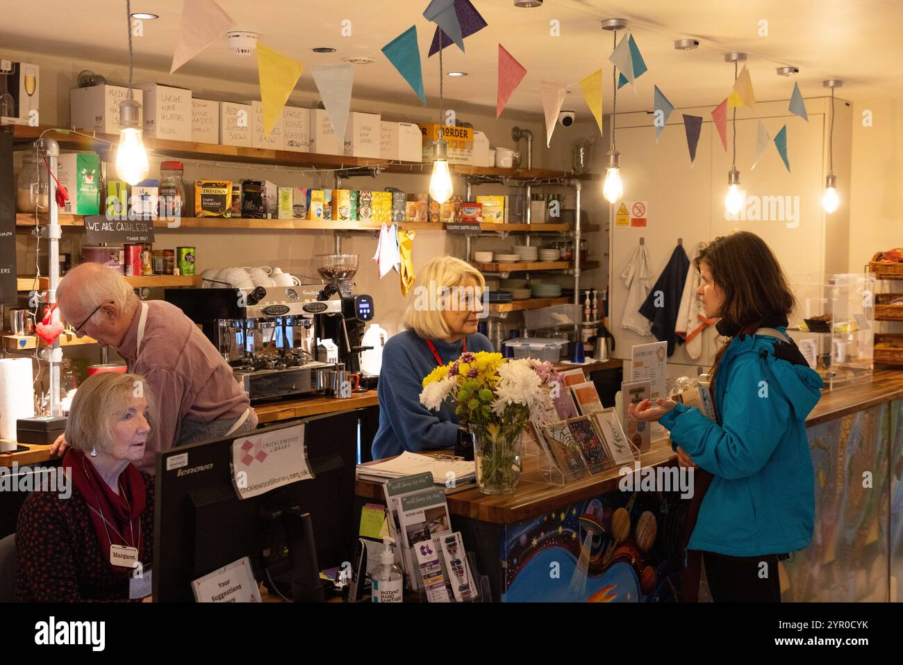 Ein Freiwilliger und ein Darlehensnehmer in der Cricklewood Library im Nordwesten Londons, die von der Gemeinde geleitet wird, nachdem der Brent council die Finanzierung eingestellt hat. Der Freiwillige li Stockfoto