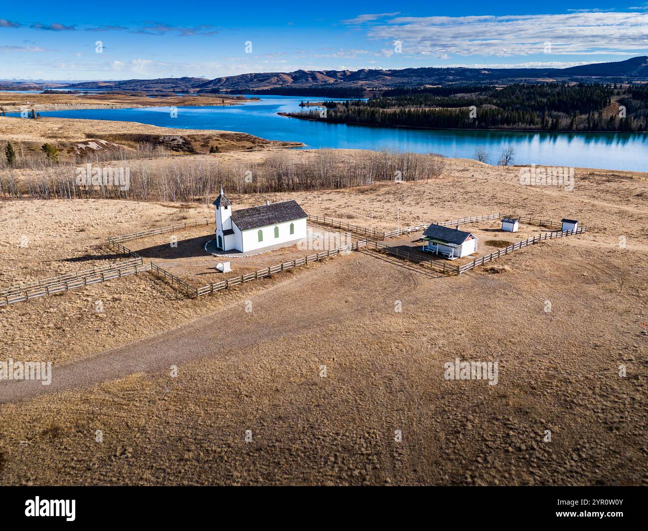 Aus der Vogelperspektive eine kleine weiße historische Kirche mit Blick auf ein Flusstal im Süden von Alberta Kanada. Stockfoto