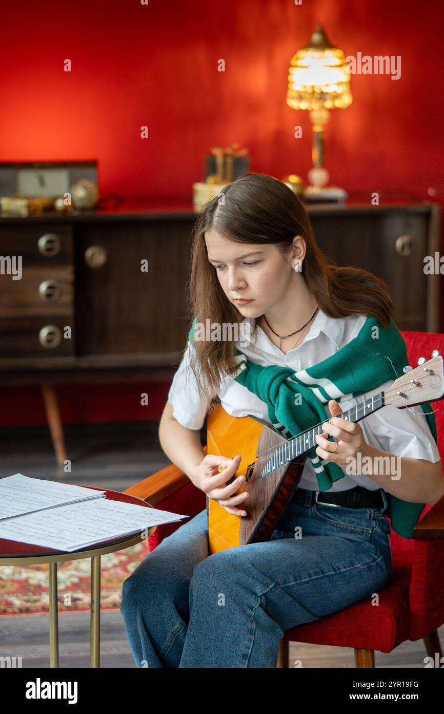 Konzentrierte Frau, die Balalaika-Lied einstudiert, Notizbogen liest, Konzert- oder Kurspraxis übt Stockfoto