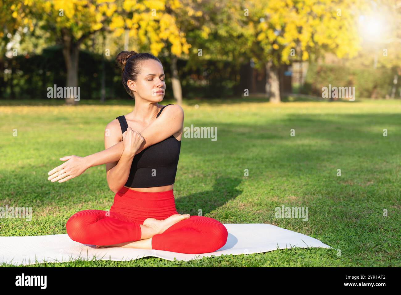 Kaukasische Frau übt Entspannungs-Yoga auf einem Rasen in einem Stadtpark. Stockfoto