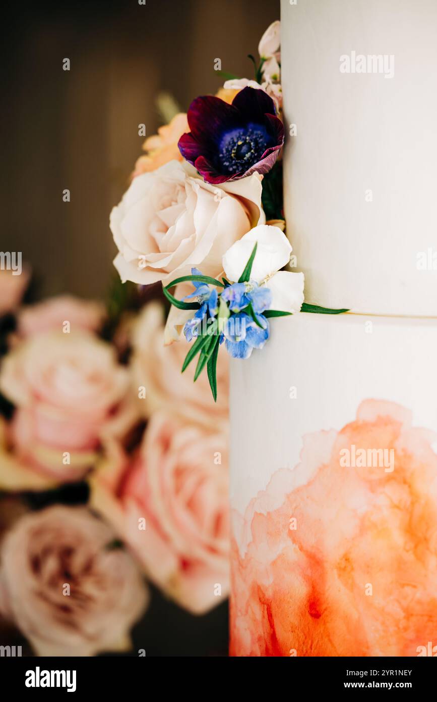 Nahaufnahme einer gestuften, handwerklichen Hochzeitstorte mit Rosenakzenten Stockfoto