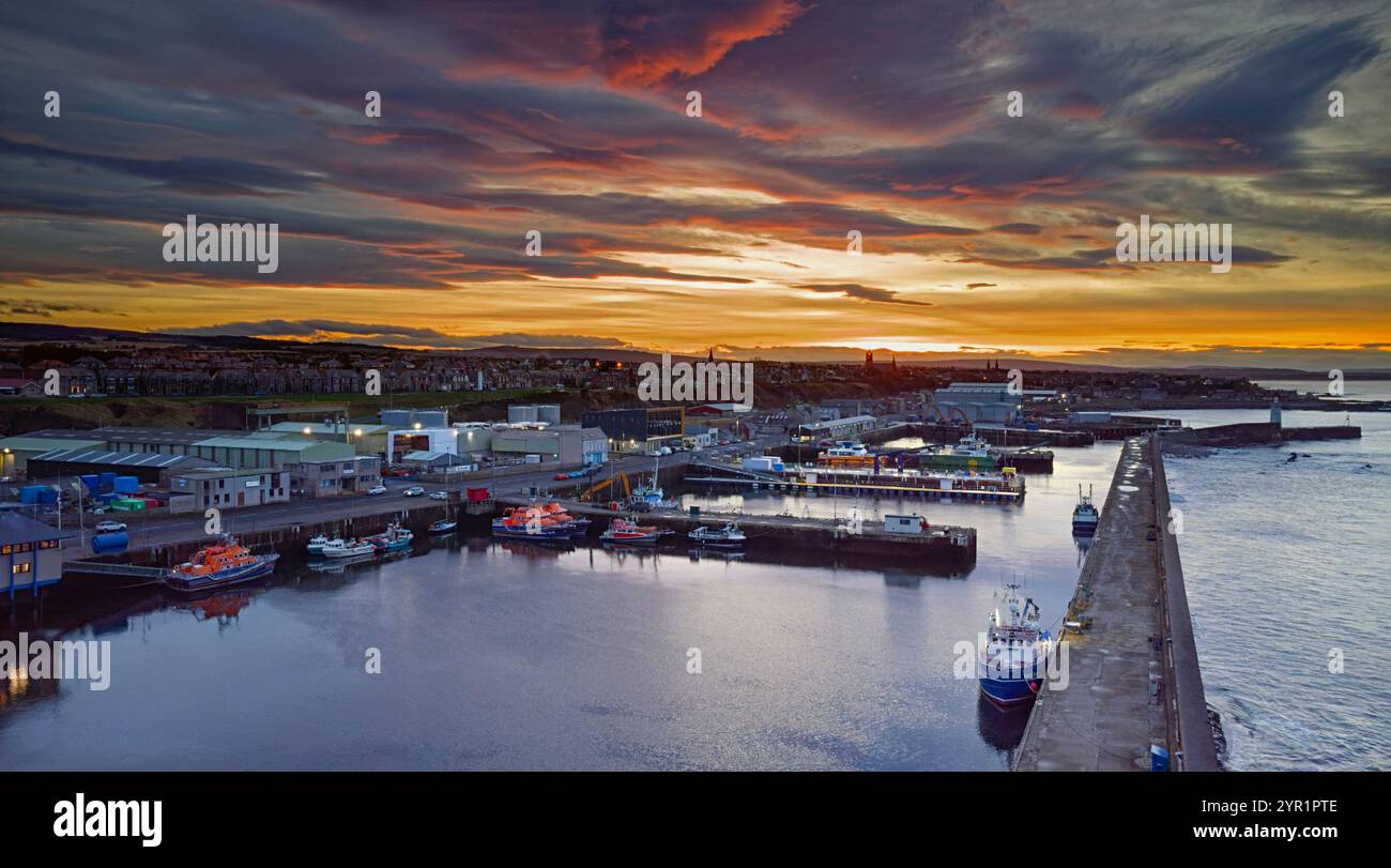 Buckie Harbour Moray Coast Scotland ein lebendiger Wintersonnenuntergang mit verankerten Rettungsbooten und Fischerbooten Stockfoto