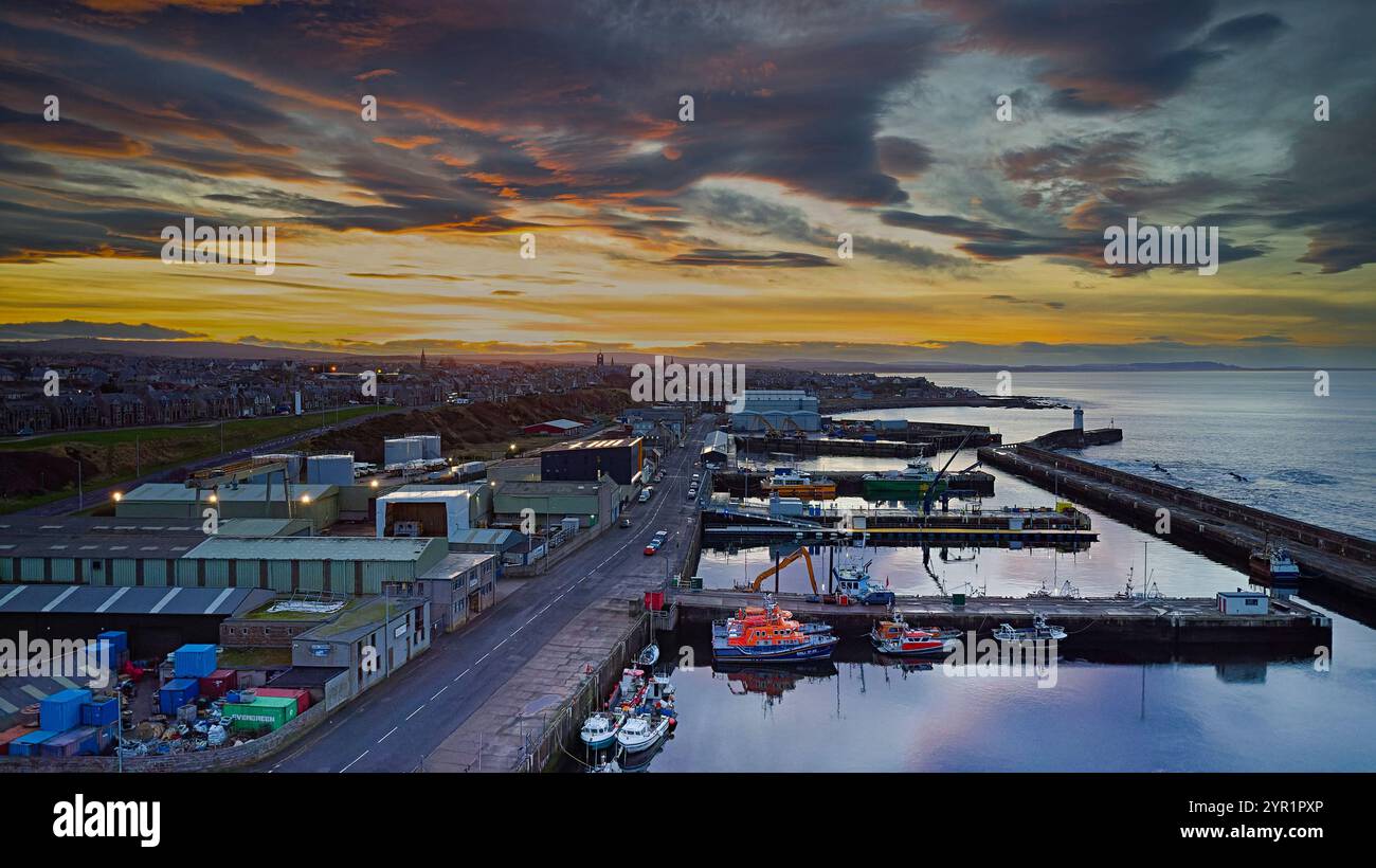 Buckie Harbour Moray Coast Schottland Winter farbenfroher Sonnenuntergang mit verankerten Rettungsbooten und kleinen Fischerbooten Stockfoto