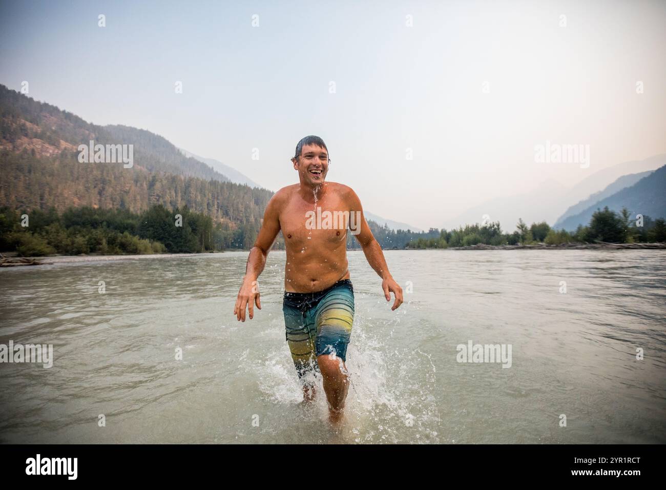 Der Mann taucht erfrischt auf, nachdem er im Squamish River geschwommen war Stockfoto