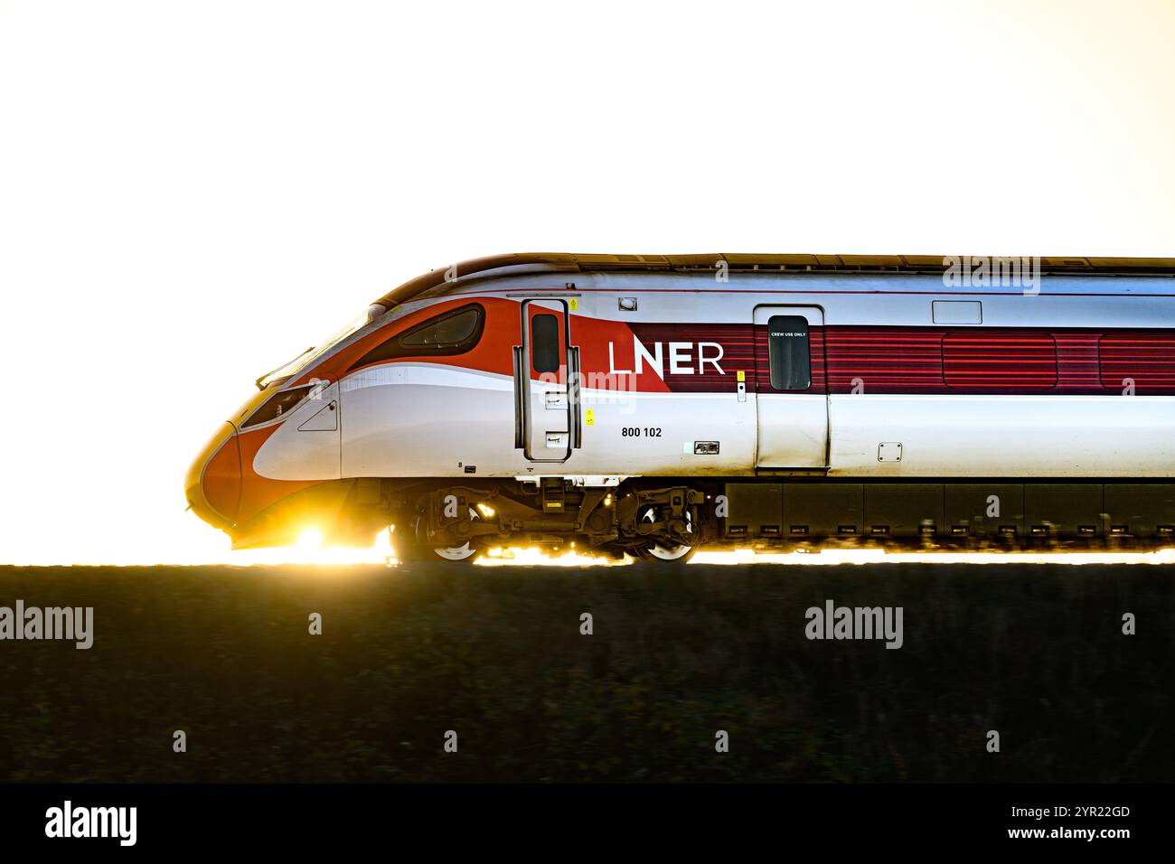 Ein LNER Azuma Train (800102), der von Einem Sonnenuntergang beleuchtet wird, während er zwischen Dalmeny und Edinburgh Gateway Stations in Schottland (Großbritannien) fährt Stockfoto