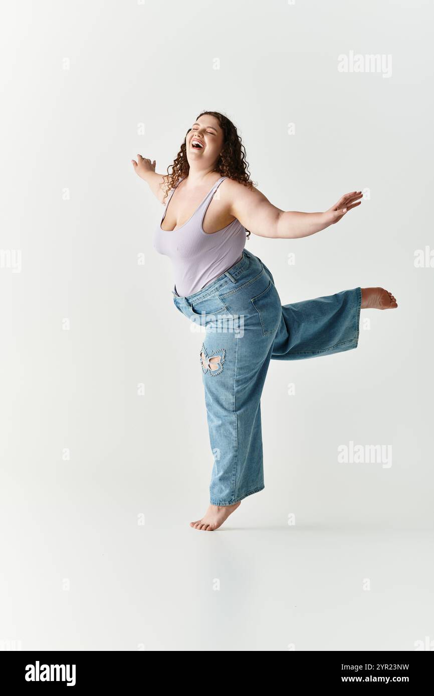 Eine junge Frau tanzt fröhlich in einem trendigen Outfit und strahlt Lebendigkeit in einem hellen Raum aus. Stockfoto
