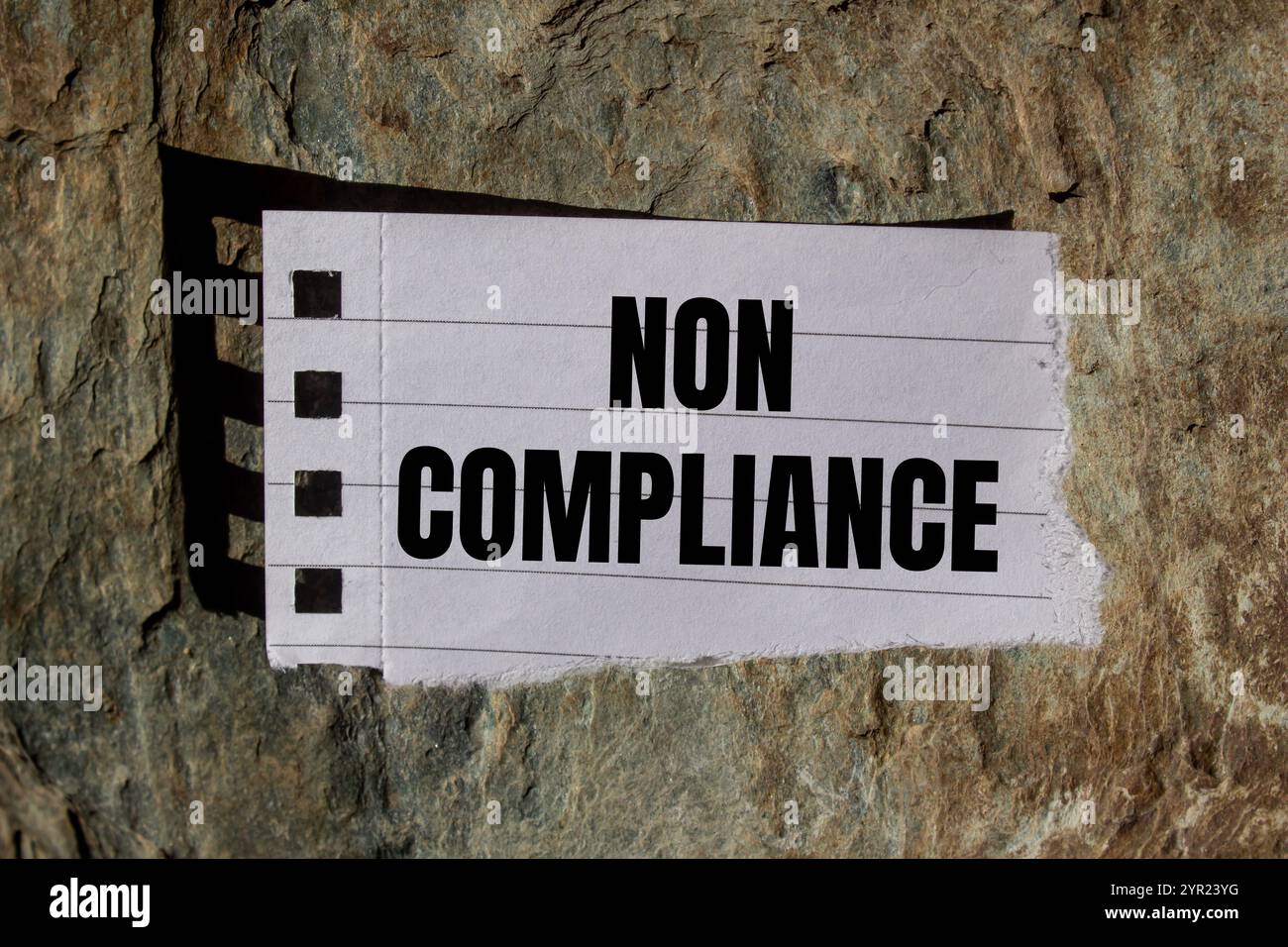 Meldung über Nichteinhaltung auf gerissenem Papierstück mit Steinhintergrund geschrieben. Symbol für konzeptionelle Nichteinhaltung. Kopierbereich. Stockfoto
