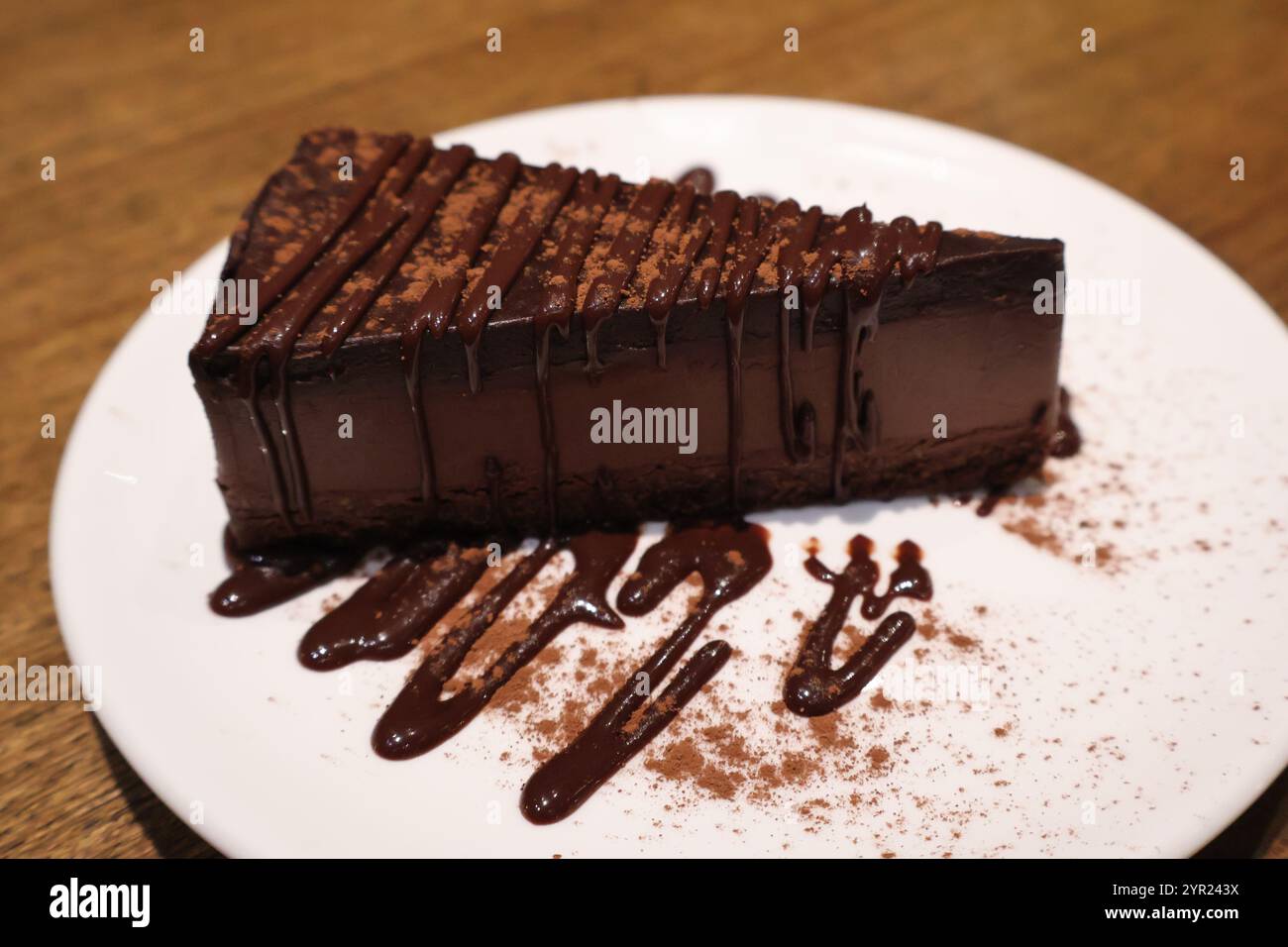 Ein dekadentes Stück Schokoladenkuchen mit reichhaltigem Schokoladengriß, serviert auf einem weißen Teller, perfekt für Dessertliebhaber und süße Genüsse. Stockfoto