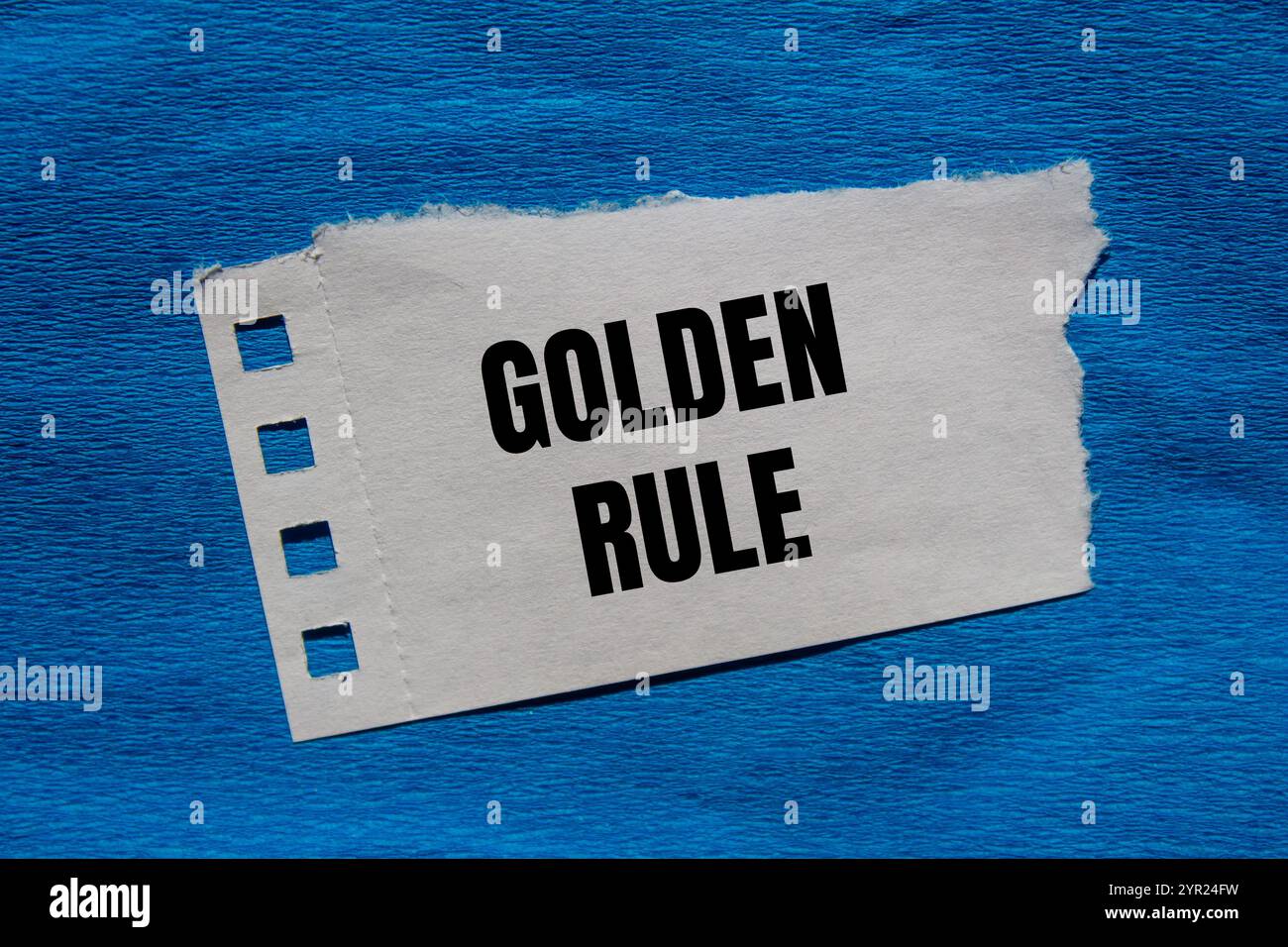 Goldene Regelnachricht auf zerrissenem Papierstück mit blauem Hintergrund. Konzeptionelles goldenes Regelsymbol. Kopierbereich. Stockfoto