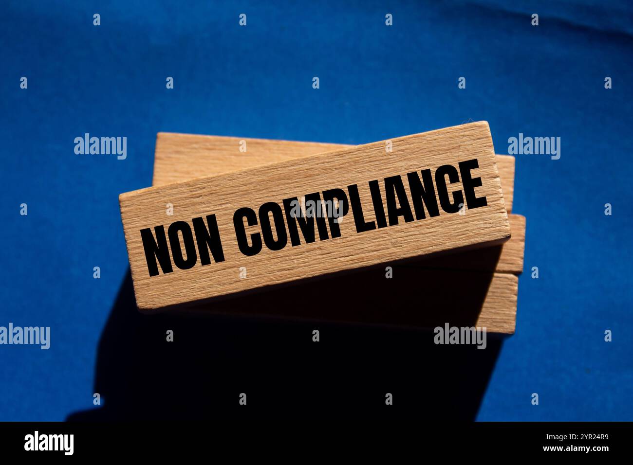 Meldung über Nichteinhaltung auf Holzblöcken mit blauem Hintergrund. Symbol für konzeptionelle Nichteinhaltung. Kopierbereich. Stockfoto