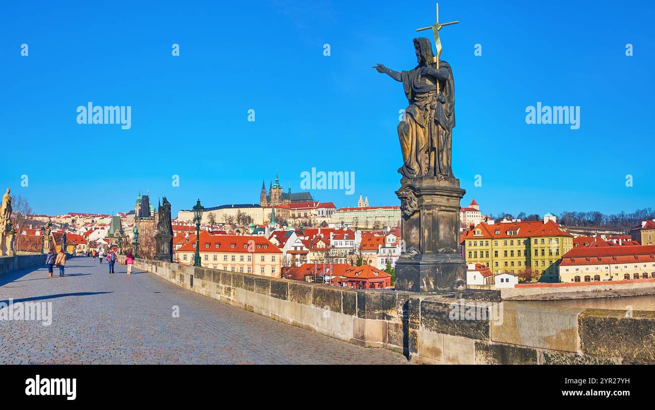 Historische Statue des Heiligen Johannes des Täufers auf der Karlsbrücke vor den roten Dächern der Mala Strana und des Veitsdoms, Prag, Tschechien Stockfoto