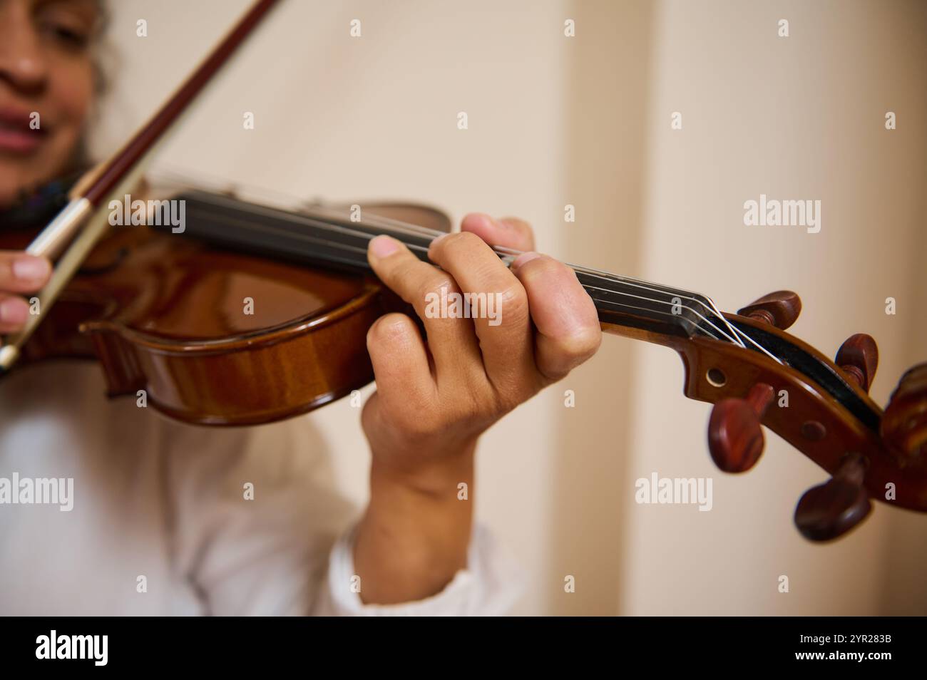 Ein detaillierter Blick auf die Hände eines Musikers, der fachmännisch Geige spielt. Das Bild vermittelt ein Gefühl von Kunst, Können und Hingabe an die Musik und zeigt die Intr Stockfoto