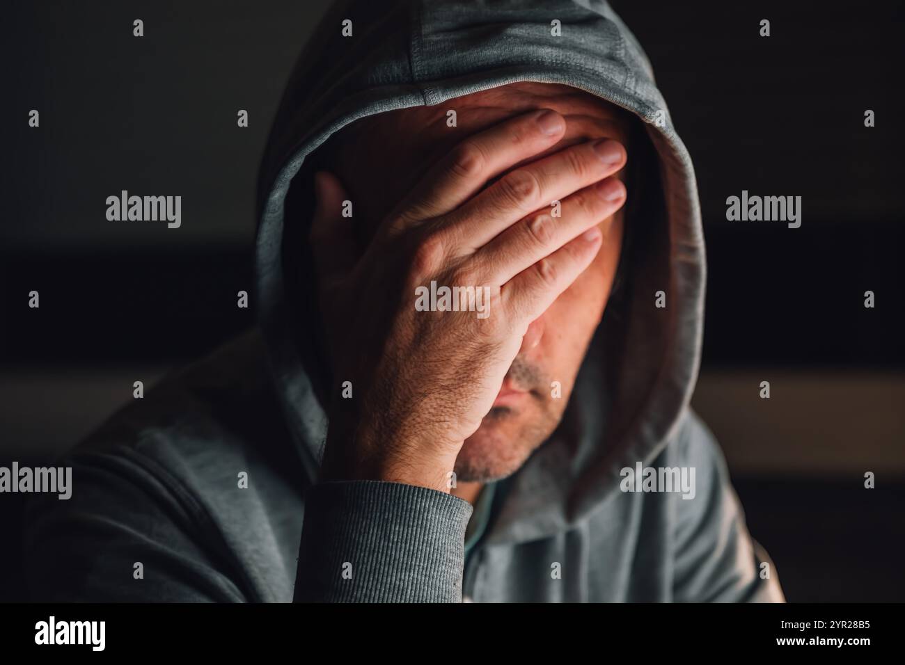 Gesichtspalme, Mann mit Kapuzenpullover im dunklen Raum, selektiver Fokus Stockfoto