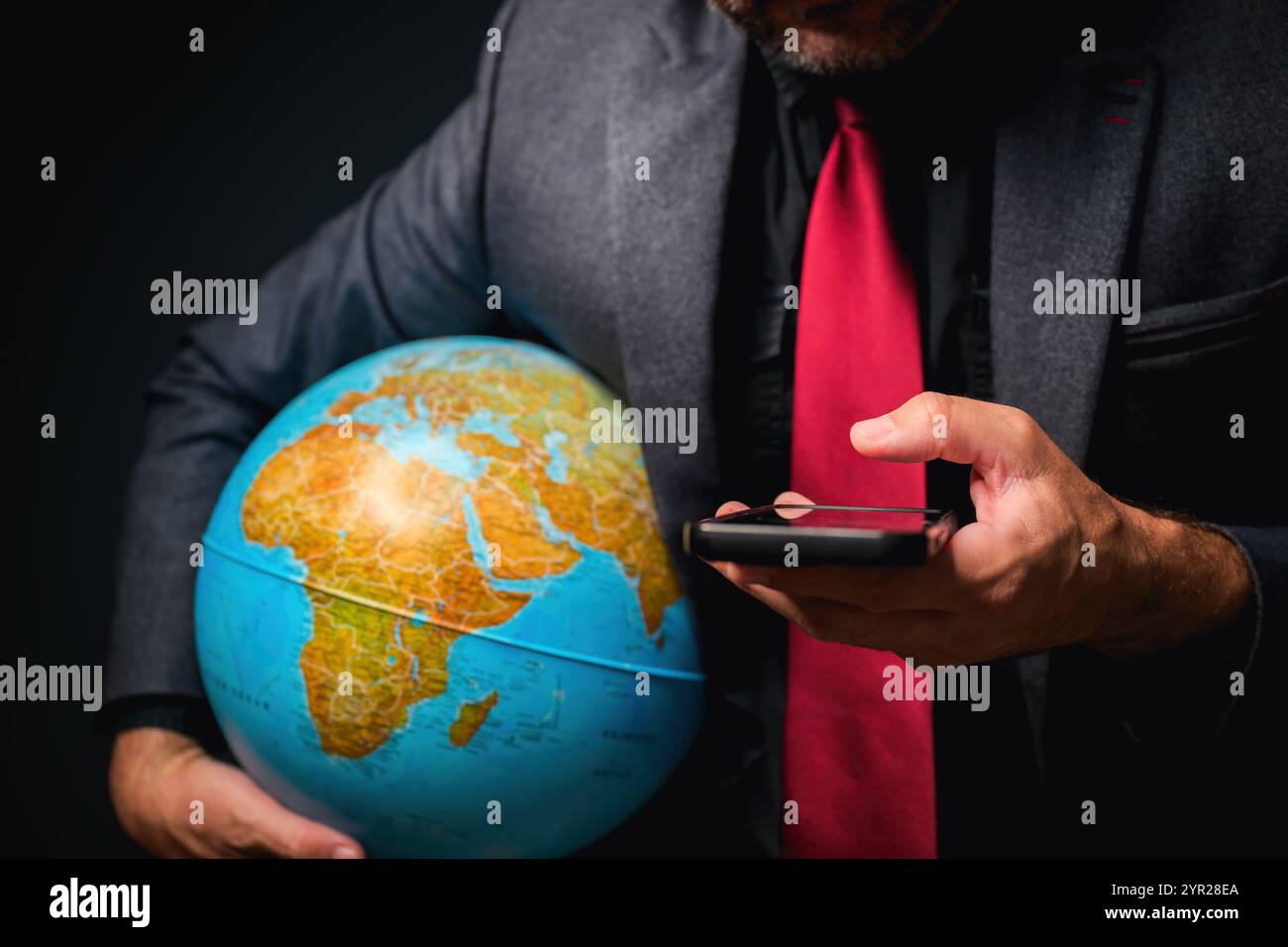 Globales Geschäftskonzept, Geschäftsmann mit Smartphone und Erdkugel in Händen, selektiver Fokus Stockfoto