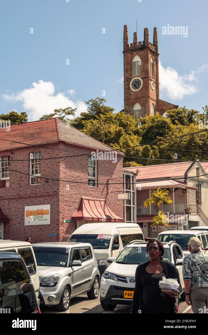 St. George's, Grenada - 4. Januar 2018: Eine geschäftige Straßenszene mit historischer Architektur und einem prominenten Kirchturm im Hintergrund. Stockfoto