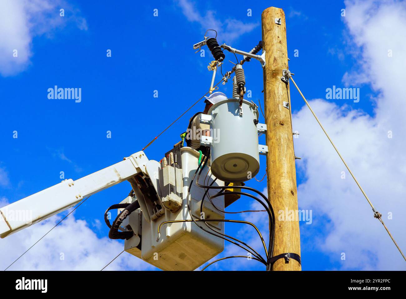 Kommunaler Kraftarbeiter im hydraulischen Hubwerk führt eine Inspektion der Hochspannungsanlagen durch. Stockfoto