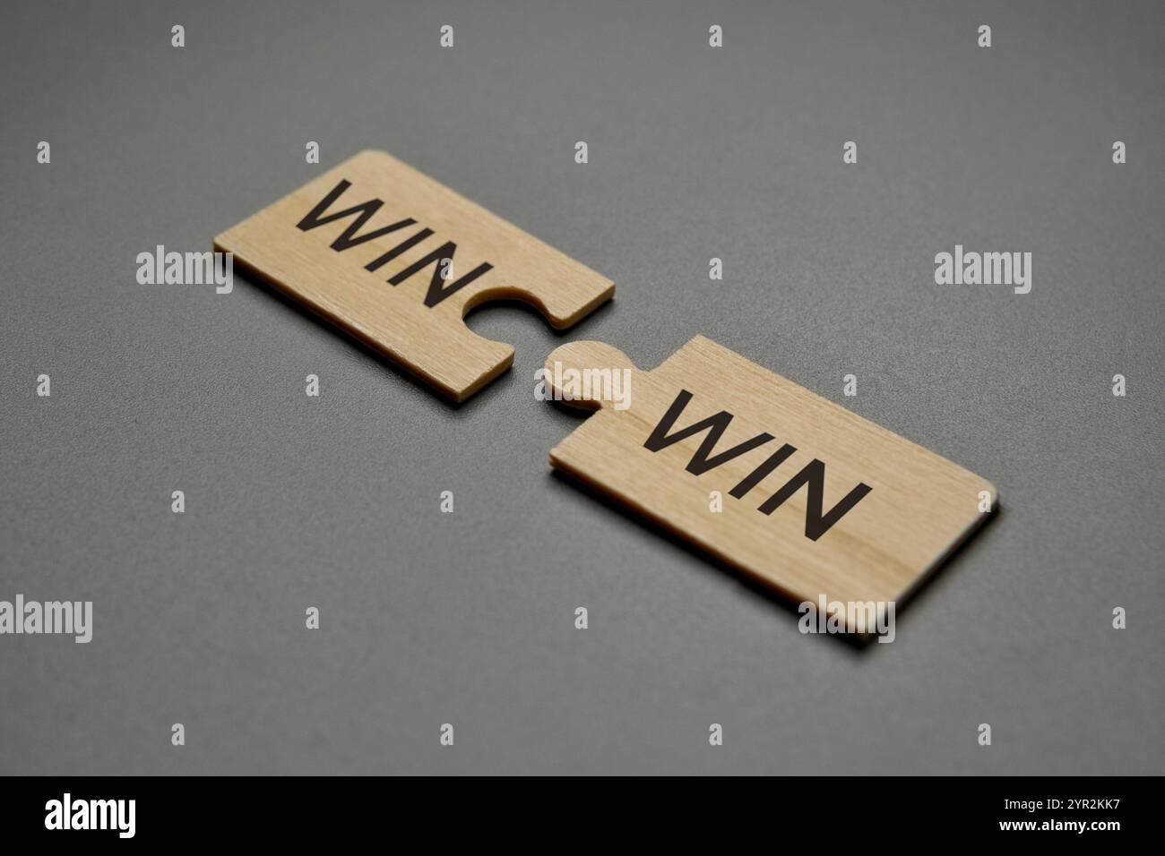 Zwei hölzerne Puzzleteile mit dem Wort „WIN“ auf jedem Stück, die perfekt zusammenpassen, um das Wort „WIN WIN“ zu bilden. Partnerschaft, Zusammenarbeit. Stockfoto