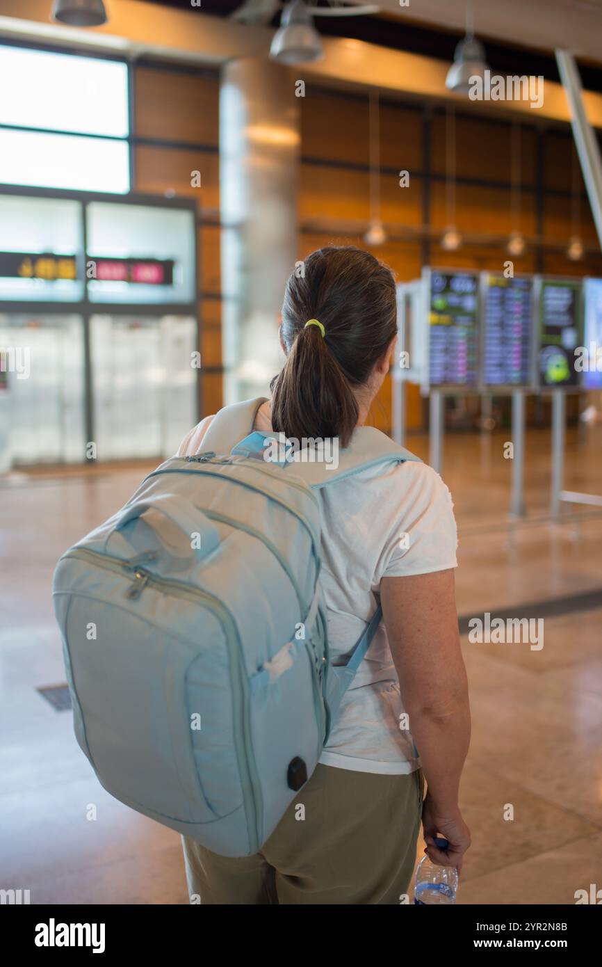 Unerkennbare Frau am Flughafen Barajas mit einem Rucksack. Alleinreisekonzept Stockfoto