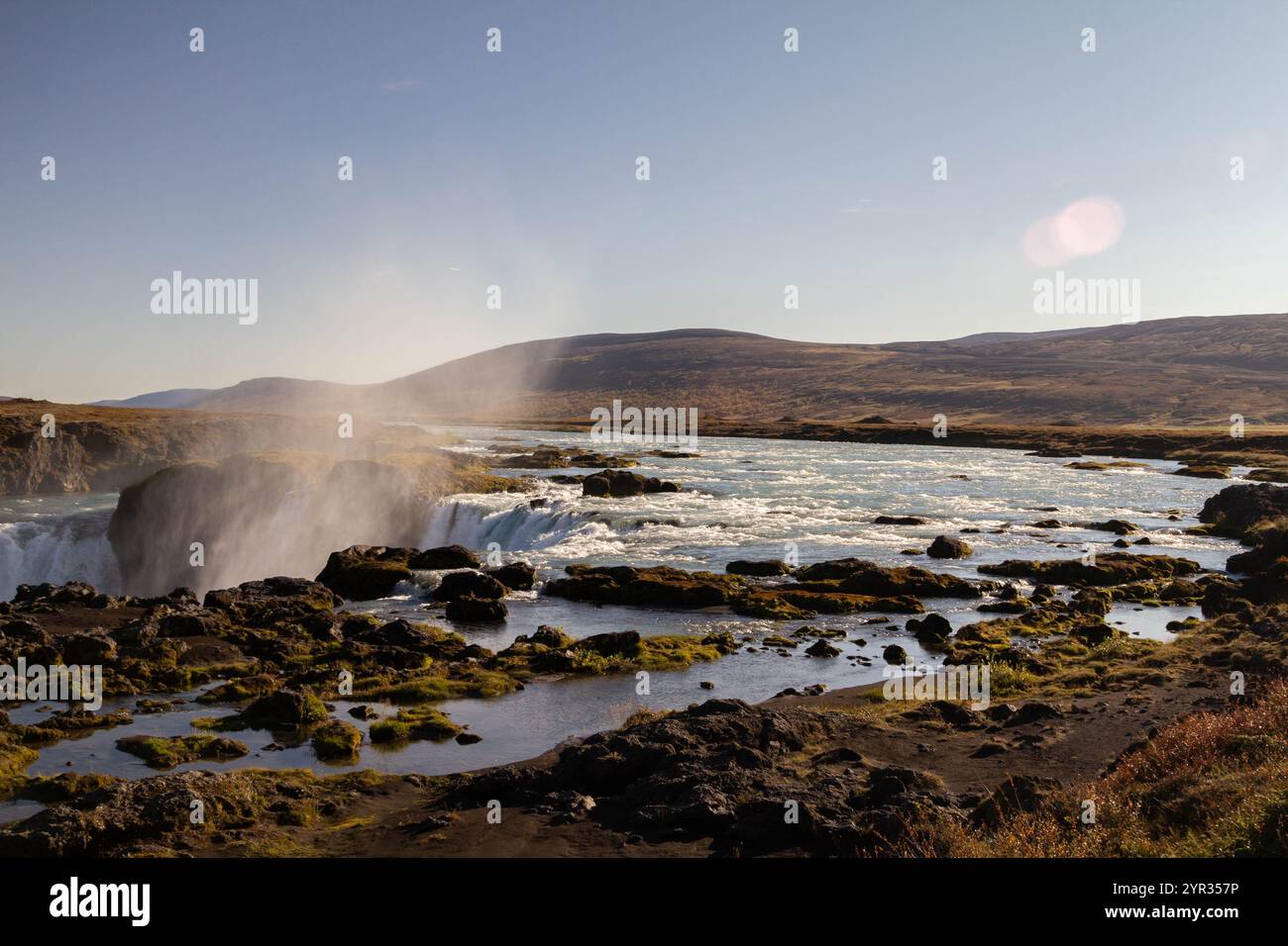 Ein ruhiger isländischer Fluss schlängelt sich durch die zerklüftete Landschaft, umgeben von Bergen Stockfoto