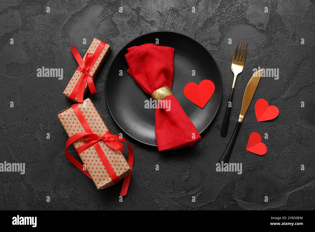 Tischeinstellung für Valentinstag mit Papierherzen, Serviette und Geschenkboxen auf schwarzem Grunge-Hintergrund Stockfoto