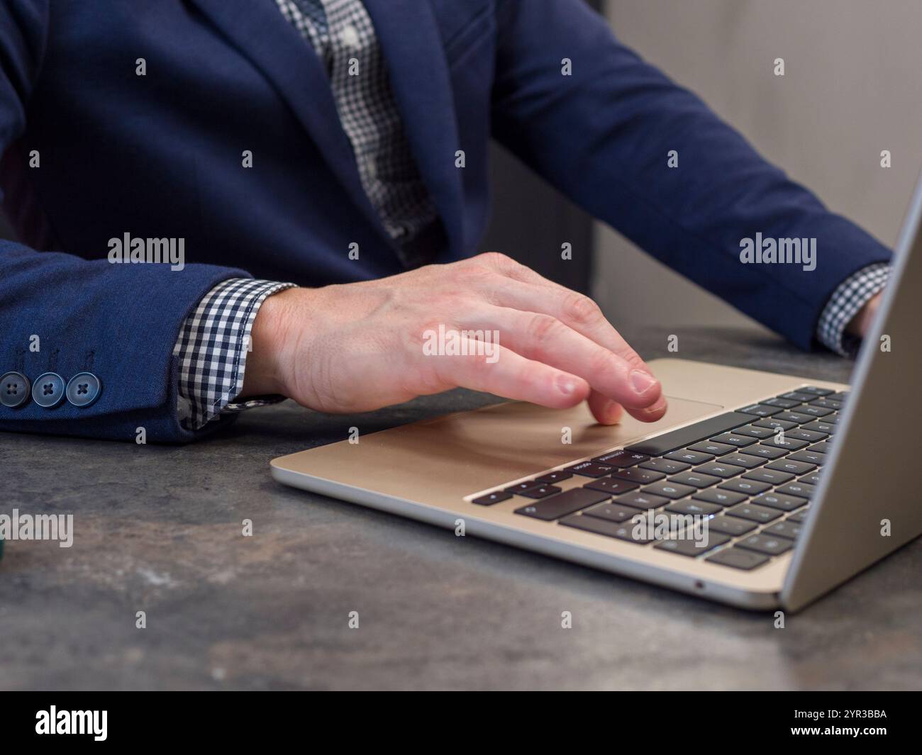 Die Person in einem modernen Büro arbeitet an einem Laptop, schreibt und surft im Internet. Er hat blaue Jacke und Knopf Stockfoto