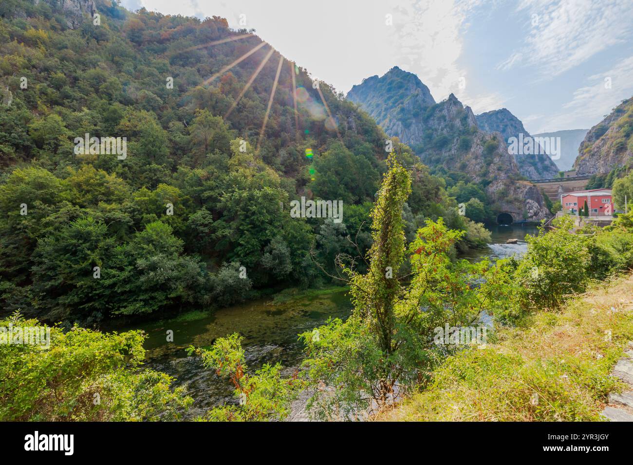 Eine Betonmauer, die sich um den künstlichen See des Matka Canyon mit Blättern und Trümmern dreht und auf der Wasseroberfläche schwimmt, und einen Metallsteg Stockfoto