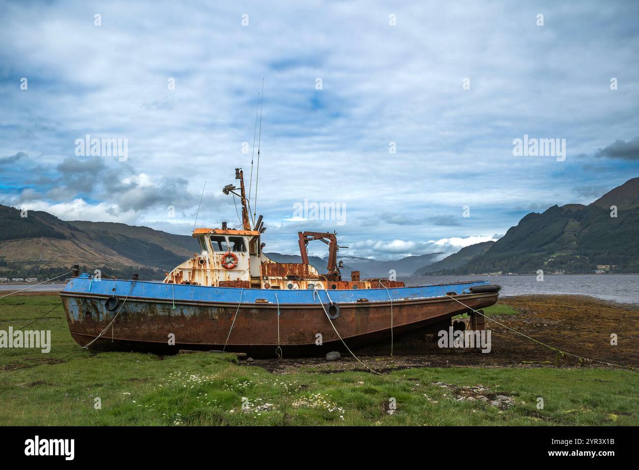 Ein altes, rostiges Boot liegt verlassen am Ufer eines schottischen Sees. Stockfoto